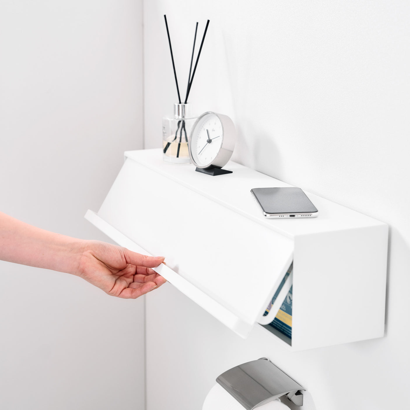 Baderom med hvit oppbevaringsboks festet over håndkleholder.