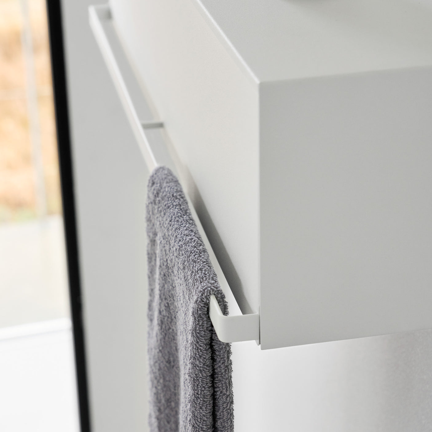 Oppbevaringsboks i hvit plast med veggfeste over vask.