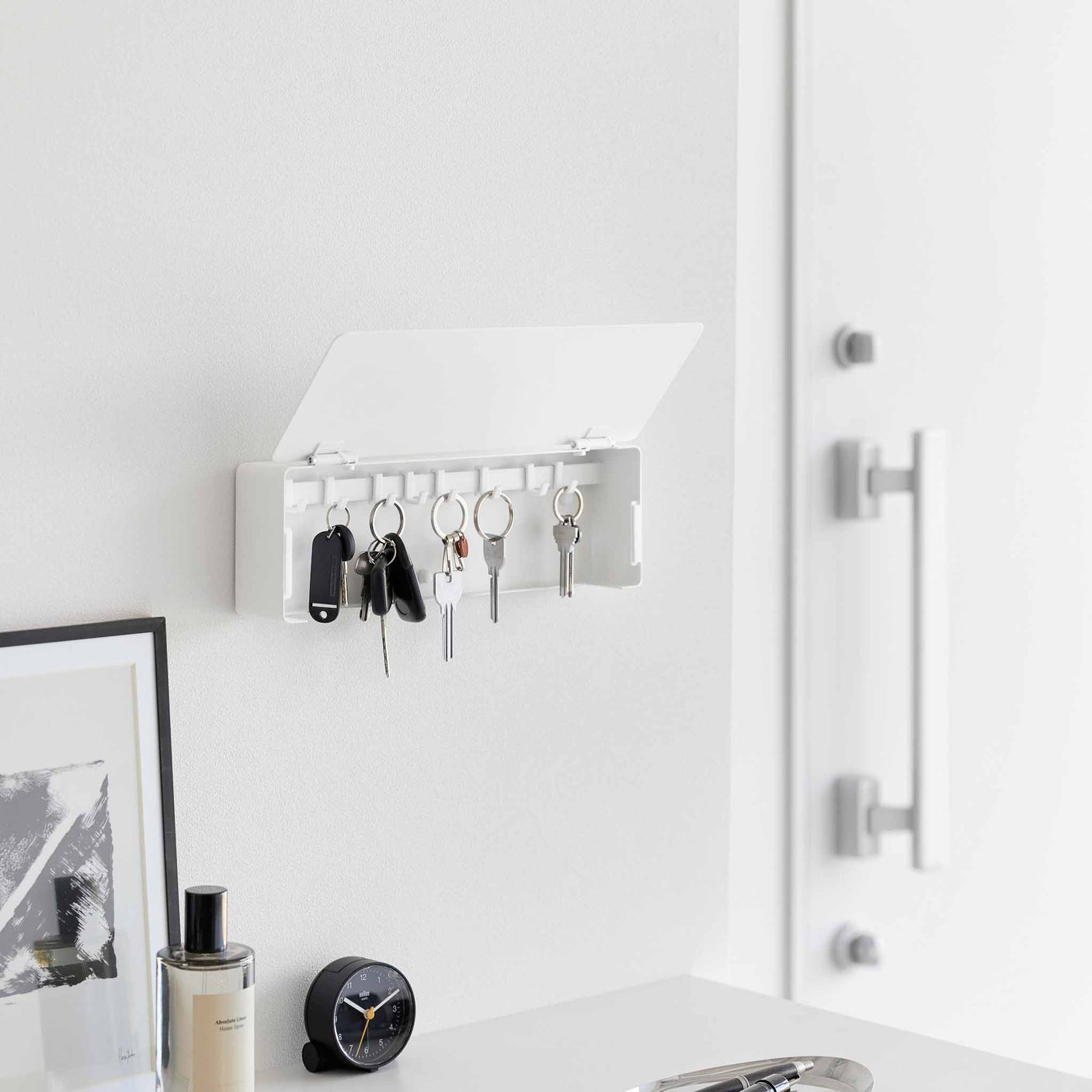 Vegghengt nøkkelskap i sort med skjult oppbevaring og flyttbare kroker