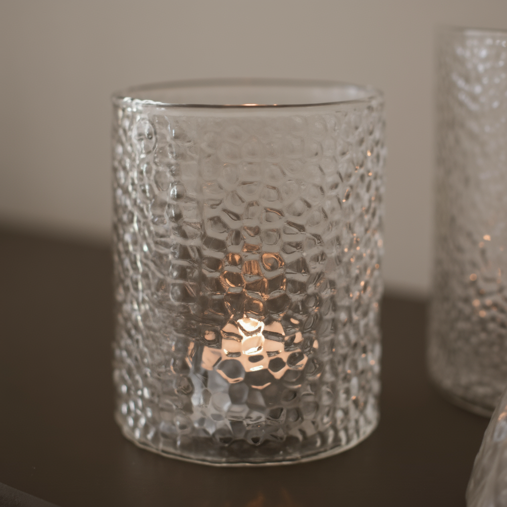 Nærbilde av en glasslykt med struktur og et lite telys inni.