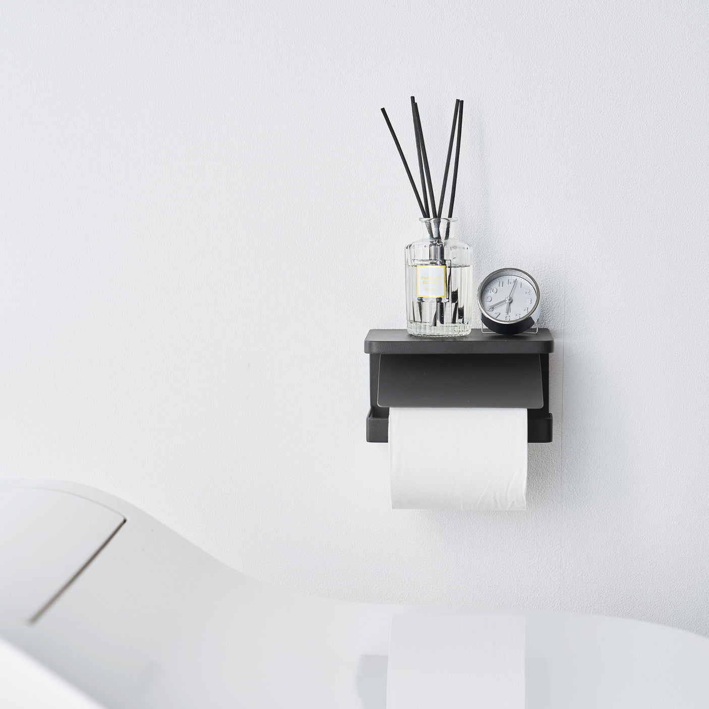 Elegant sort toalettpapirholder i metall, veggmontert modell med hylle til små baderomsartikler