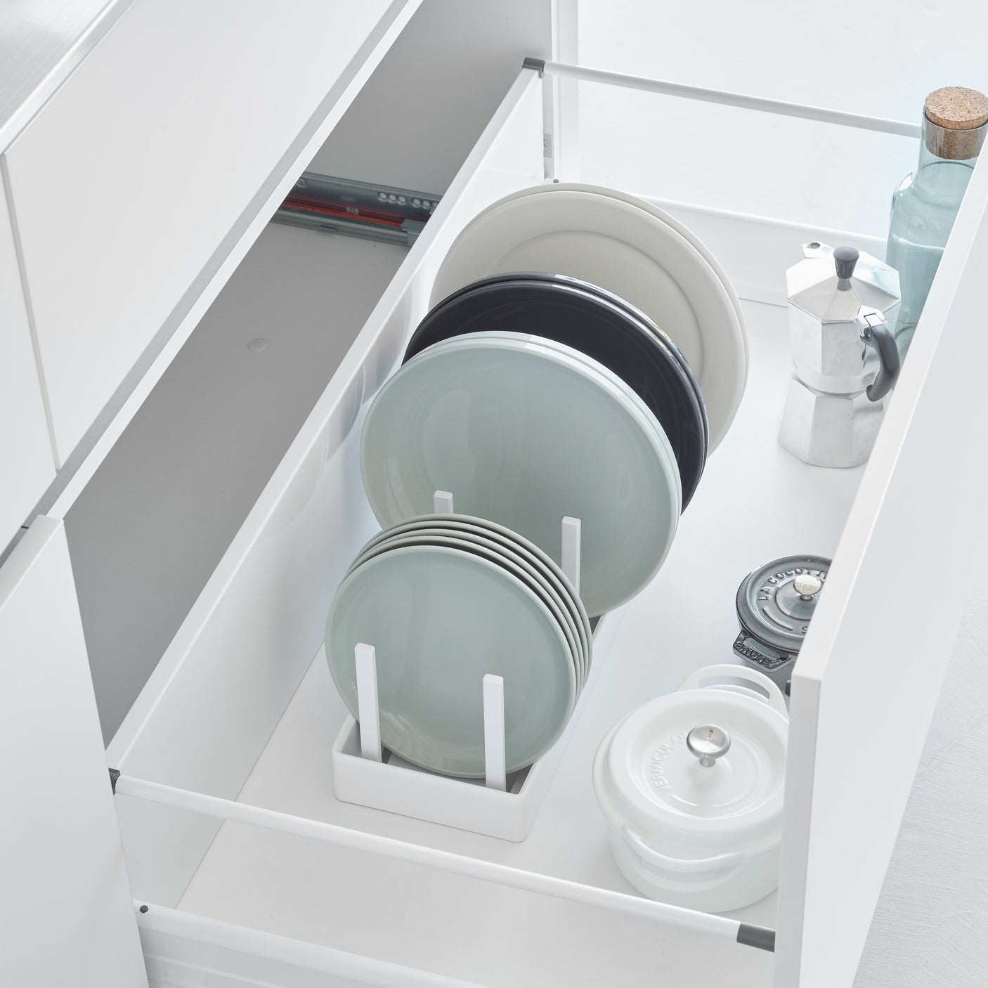 Hvit justerbar gryte- og lokkholder med skillevegger i kjøkkenskuff.