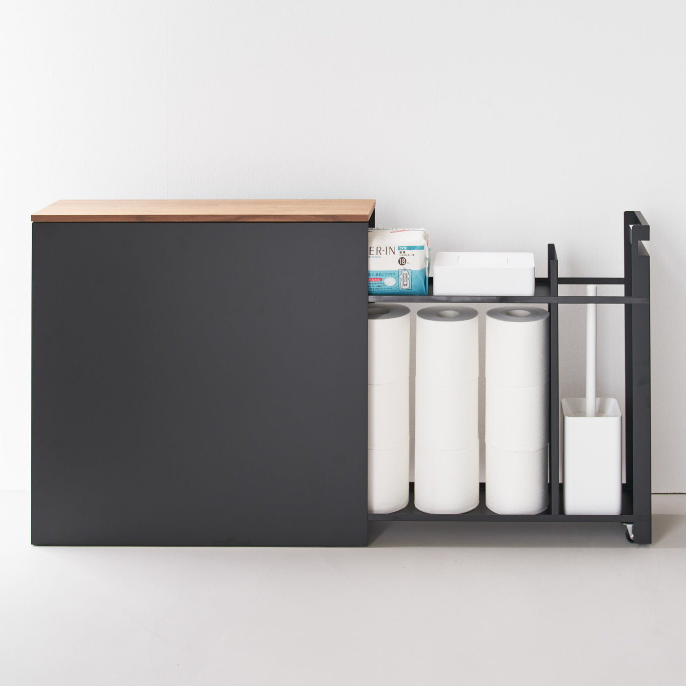 Smal sort hylle med skyvbar topp og skjult oppbevaring på bad.