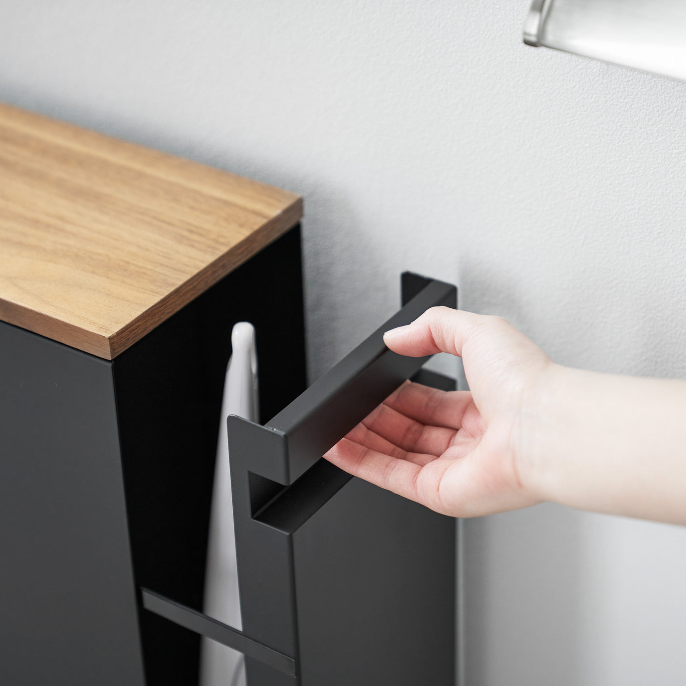 Detaljbilde av skyvbar topp i tre på sort oppbevaringshylle.