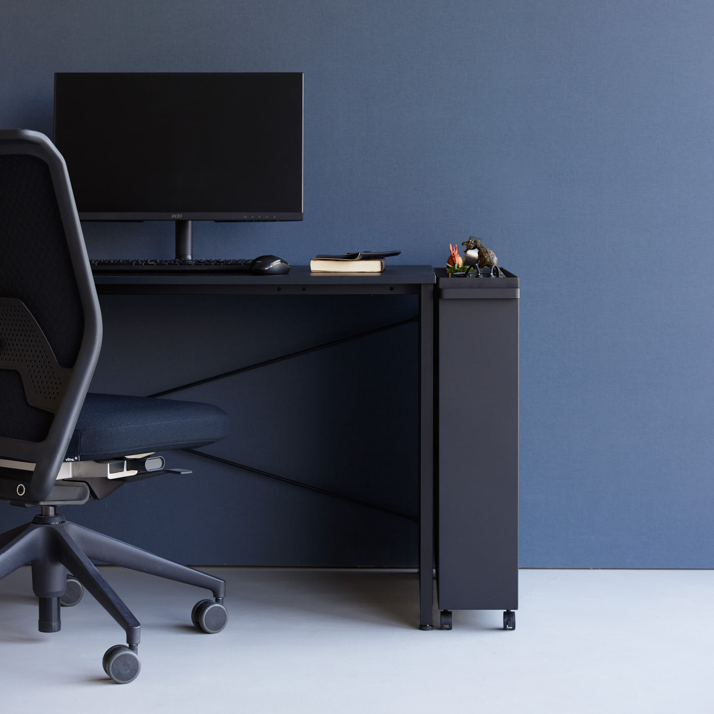 Smal sort hyllevogn med bøker og dekor i stue.