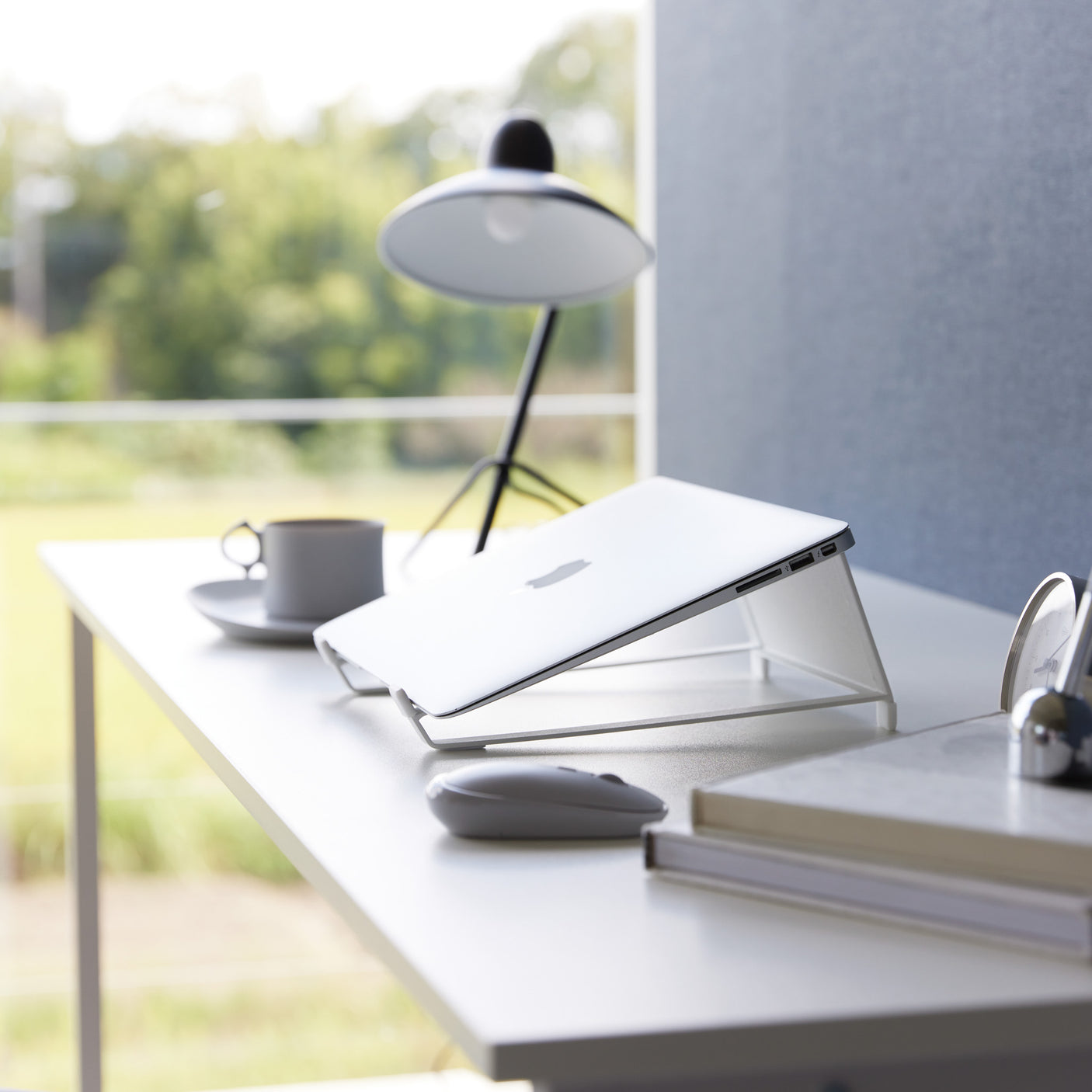 Hvit laptopstativ brukt i hjemmekontor med moderne innredning.