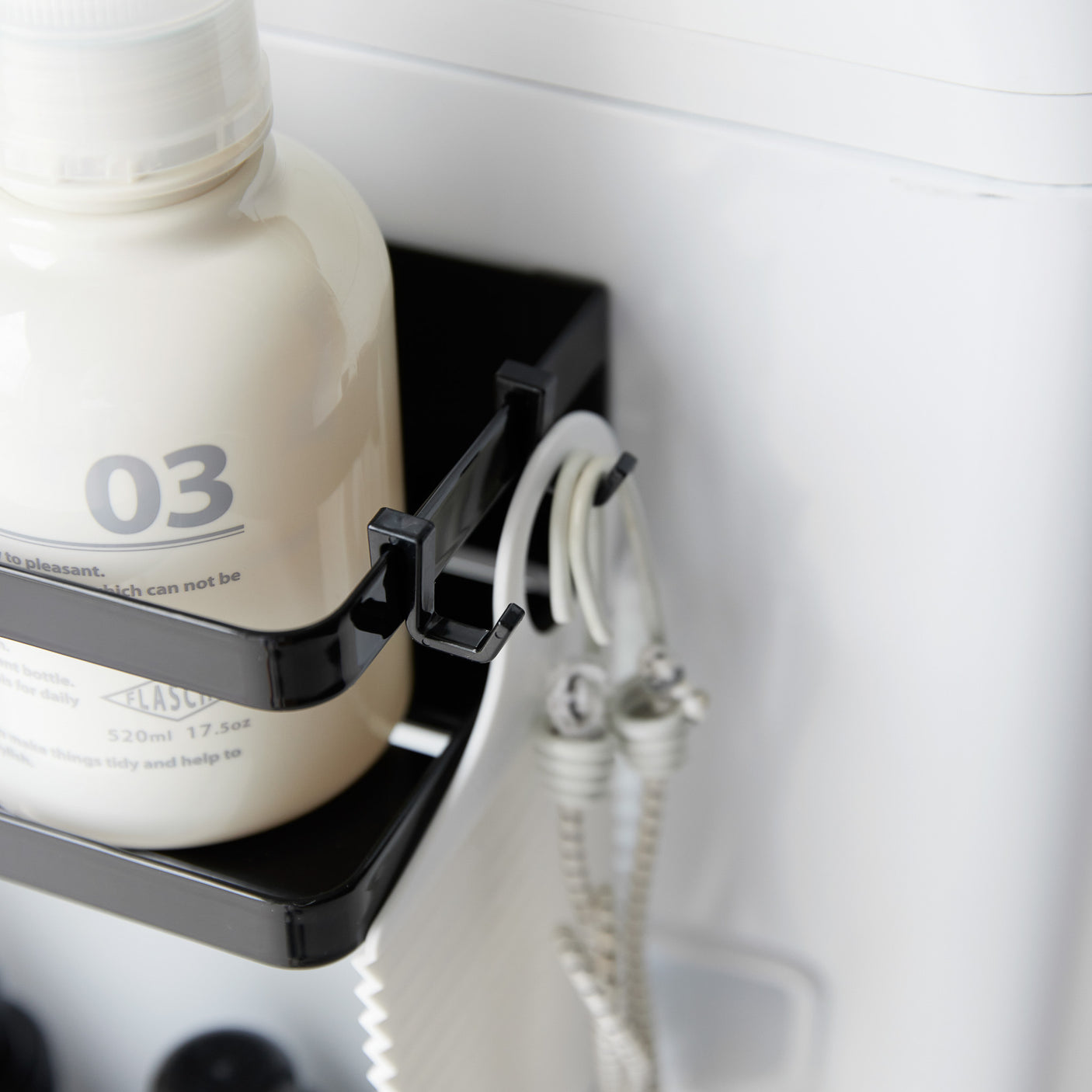 Magnetisk oppbevaringshylle på vaskemaskin med flasker og håndklær.