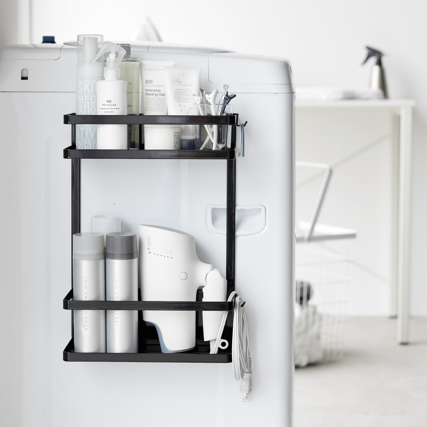 Sort magnetisk oppbevaringshylle festet på vaskemaskin med rengjøringsprodukter.