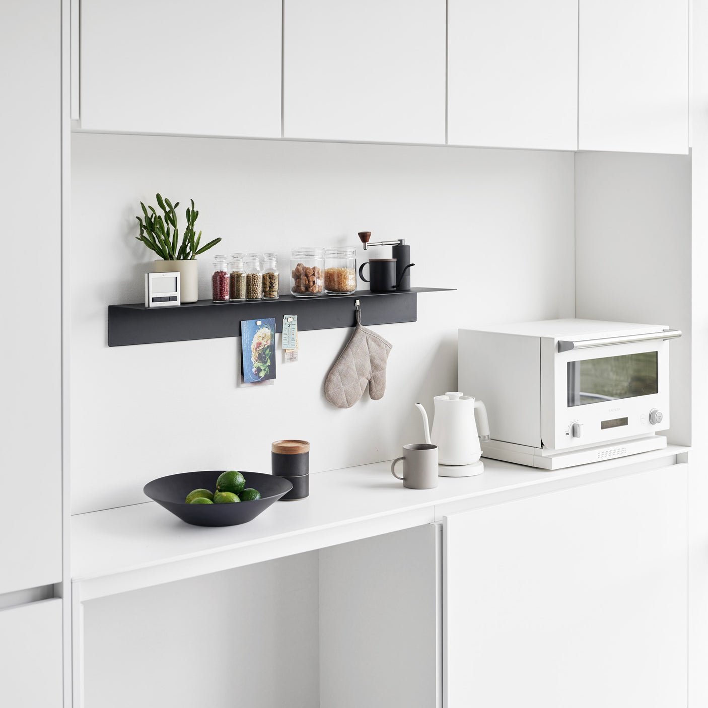 Hvite veggmonterte hyller med bøker og dekor i stue