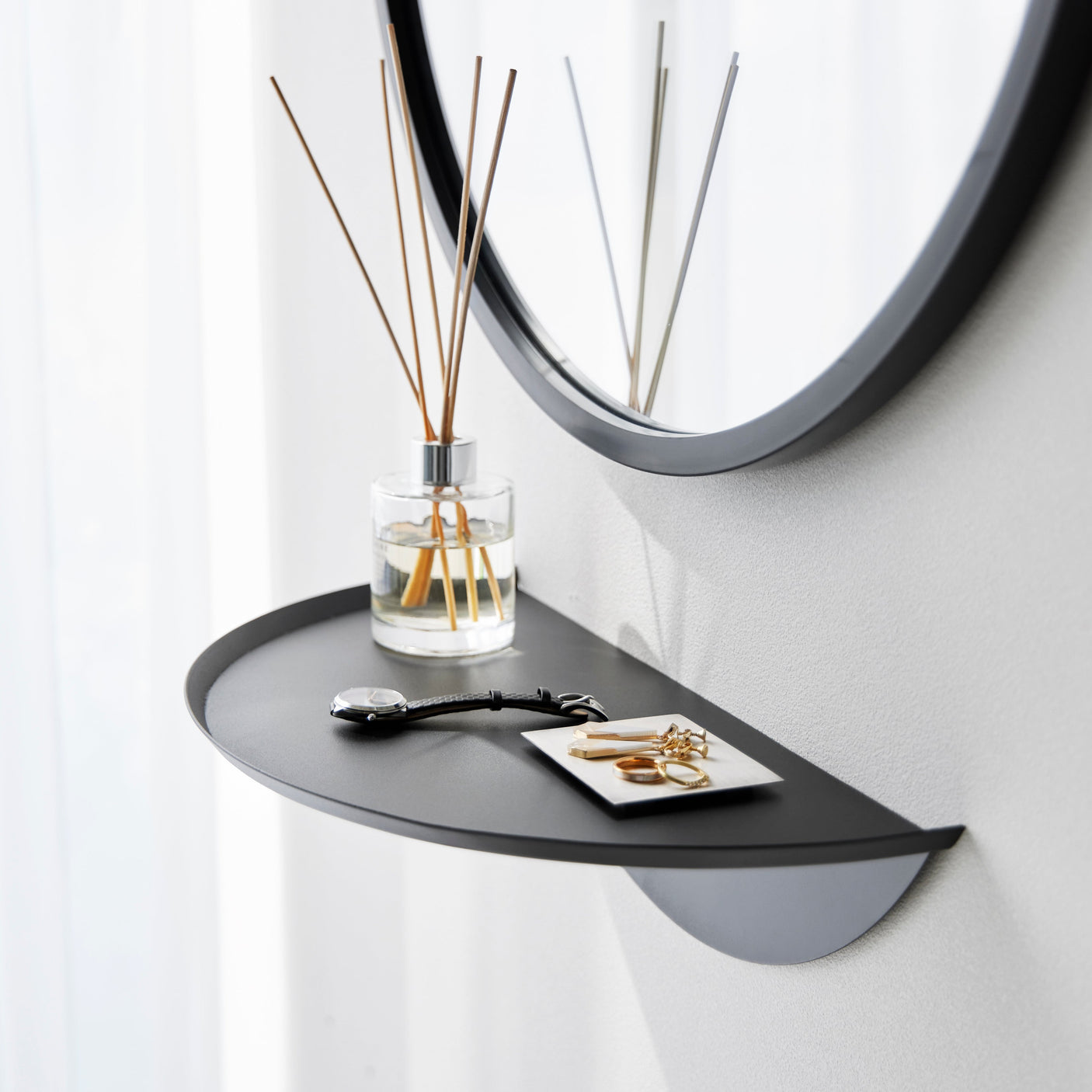 Halvrund vegghylle i sort metall for praktisk oppbevaring.