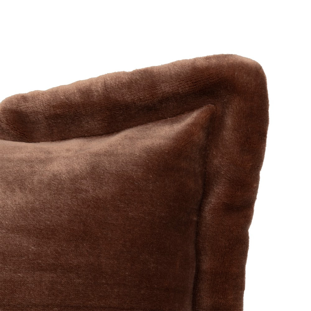 Brun flanellpute i sofa blant lyse puter