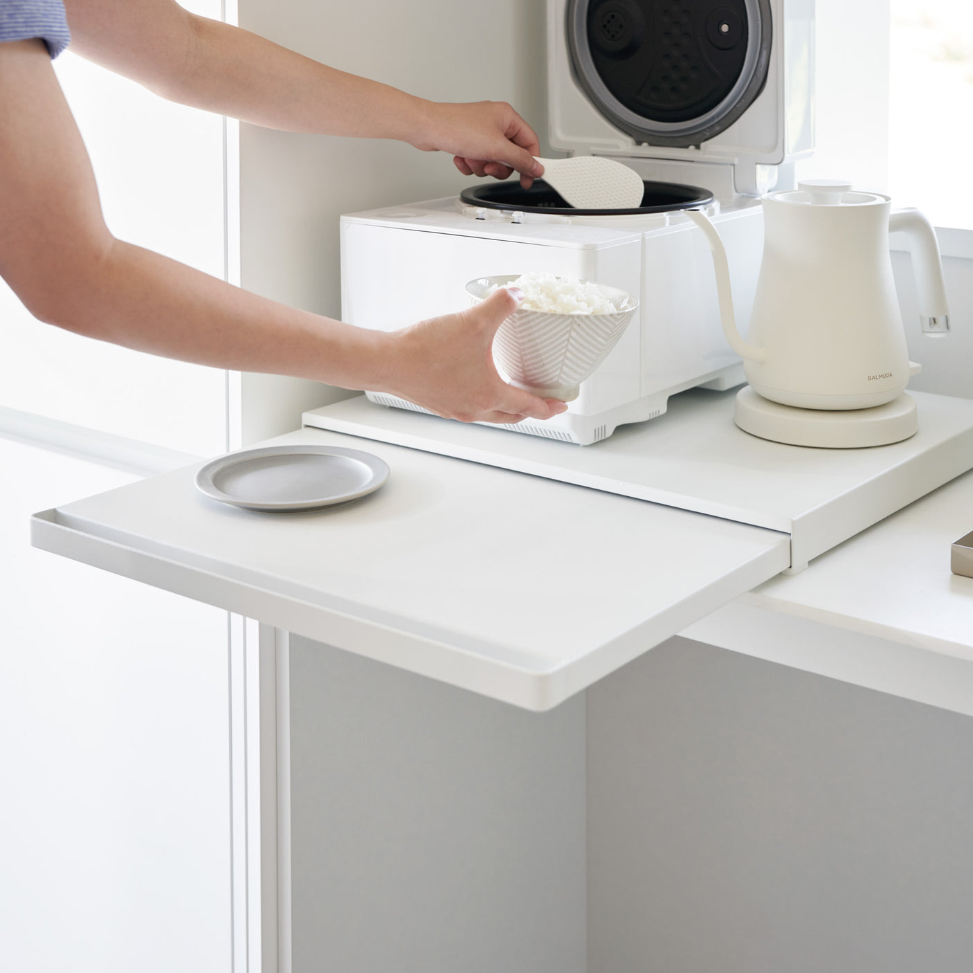 Person som bruker uttrekkbar hylleplate som ekstra arbeidsplass