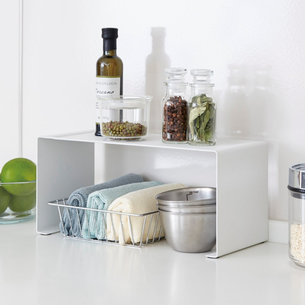 Hvit stablehylle for organisering av kjøkkenutstyr og krydder.