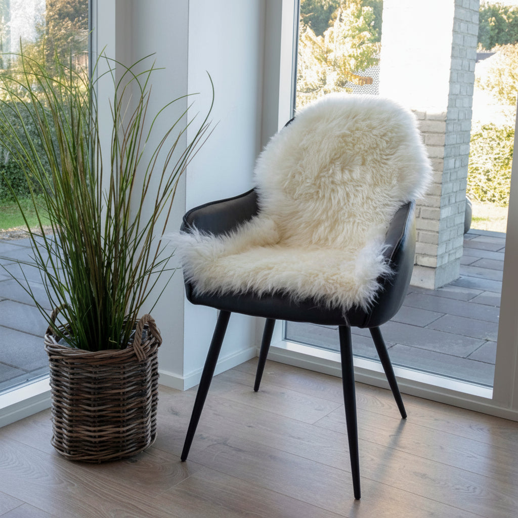 Dekorativt lammeskinn i ivory brukt som sitteunderlag på stol.