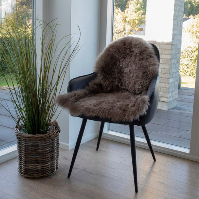 Elegant grå lammeskinn brukt på moderne stol for myk komfort.