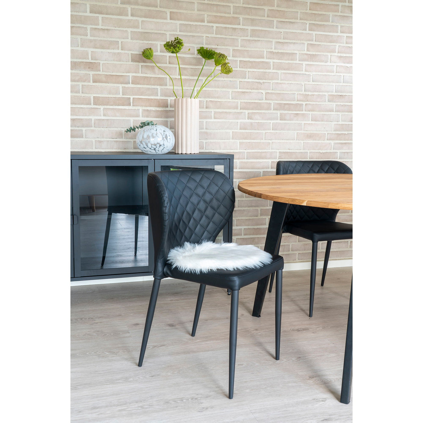 Flere stoler med hvite sitteunderlag i kunstig saueskinn rundt spisebord