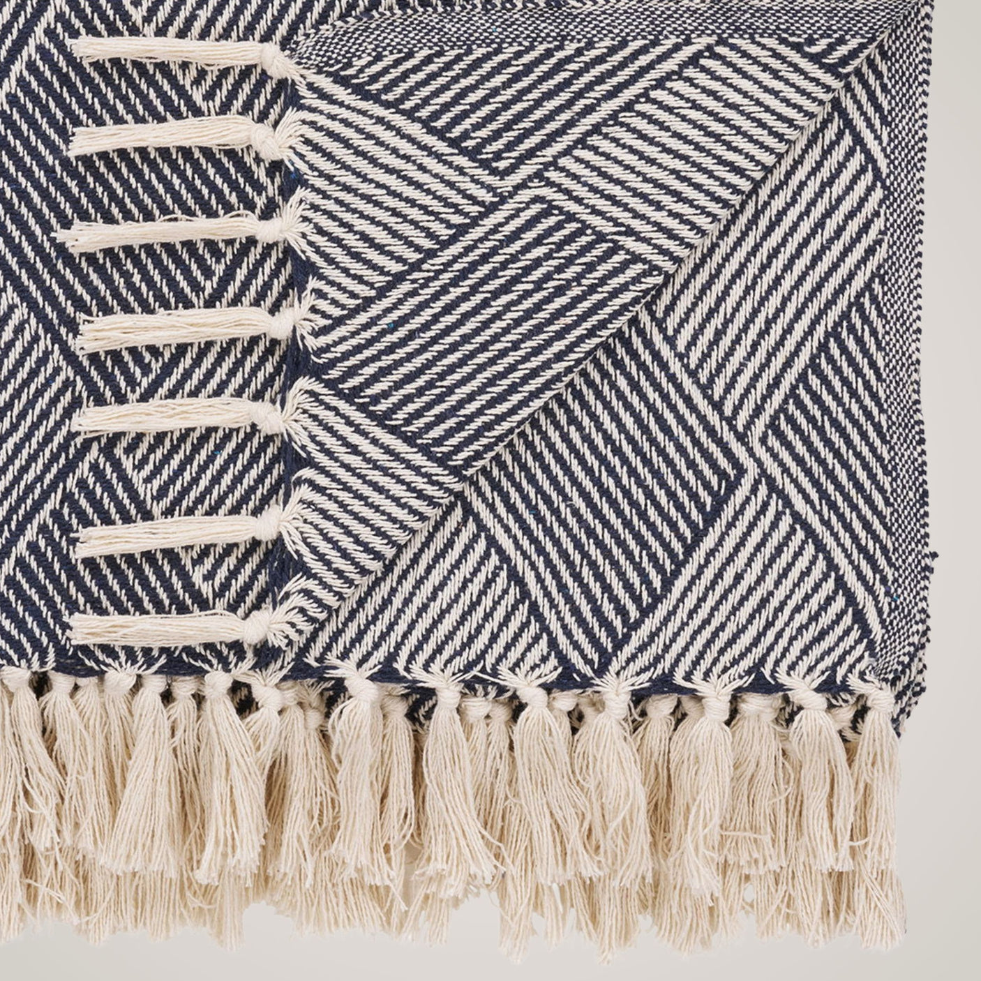 House Nordic Izmir pledd i blått og beige med geometrisk mønster og dekorative frynser – mykt og stilfullt teppe til sofa eller seng.
