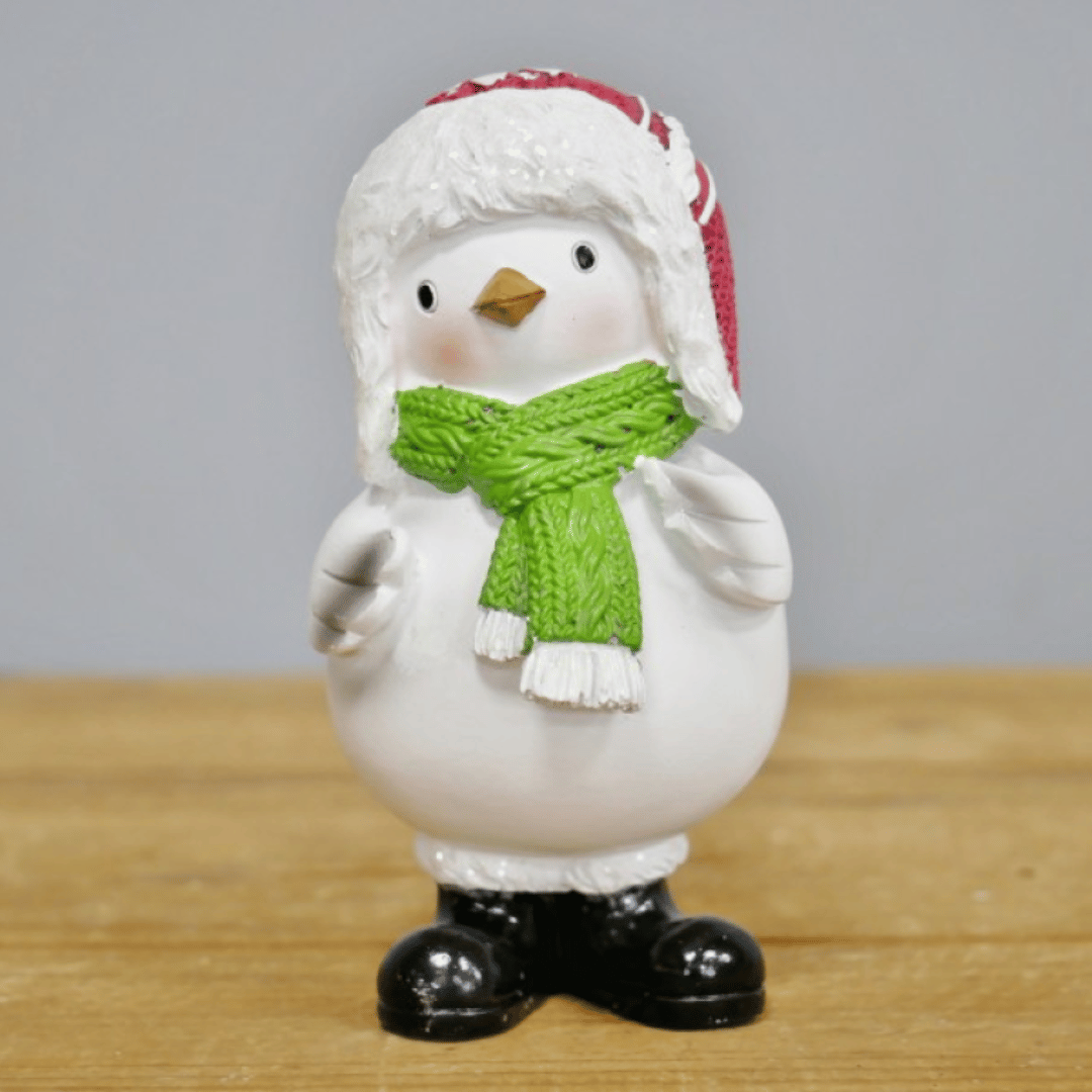 Julefugl i hvit keramikk med rød lue, grønt skjerf og svarte støvler.