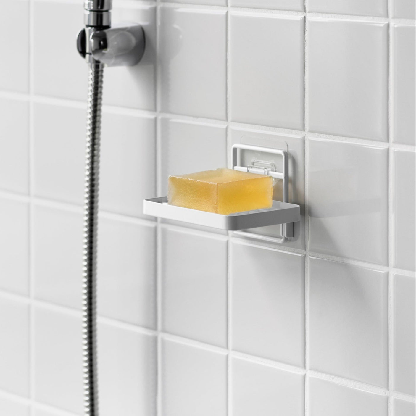 Hvit veggmontert såpeholder med selvklebende feste.