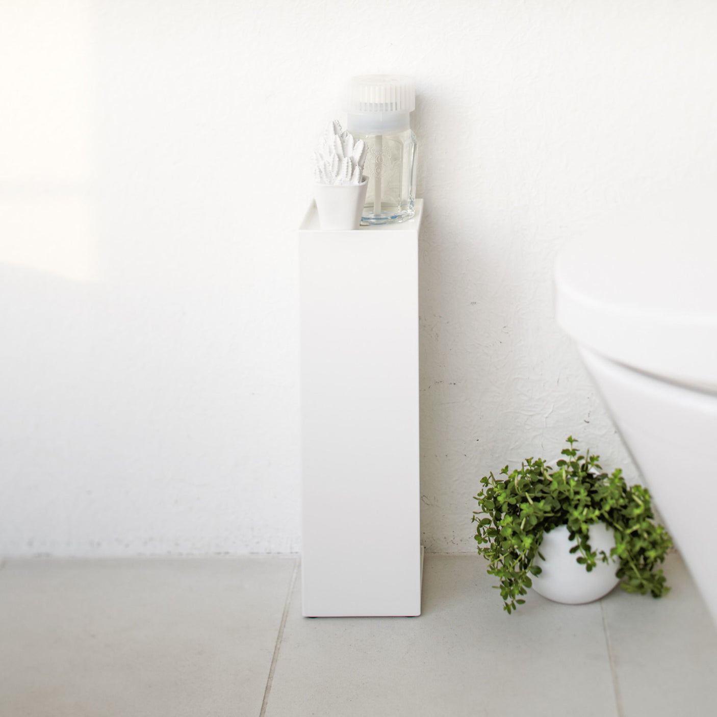 Hvit dorullholder med smal og plassbesparende utforming.