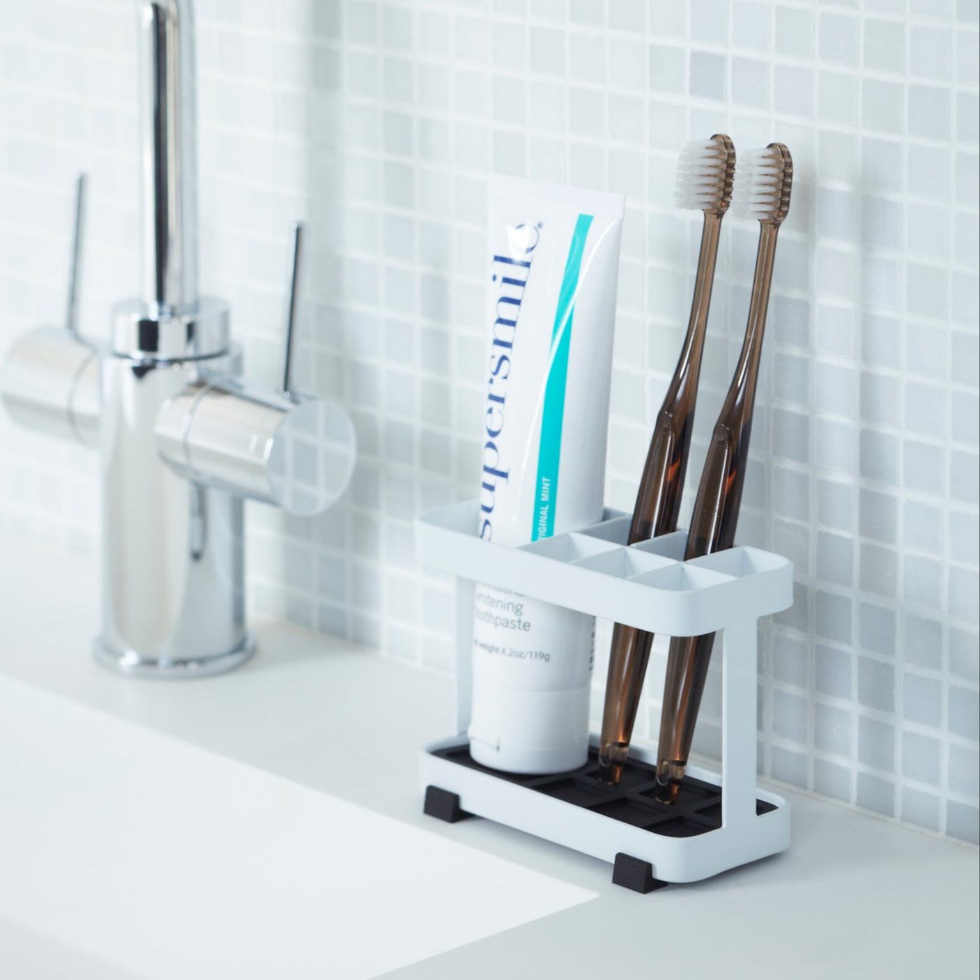 Hvit tannbørsteholder med plass til tannkrem og børster.