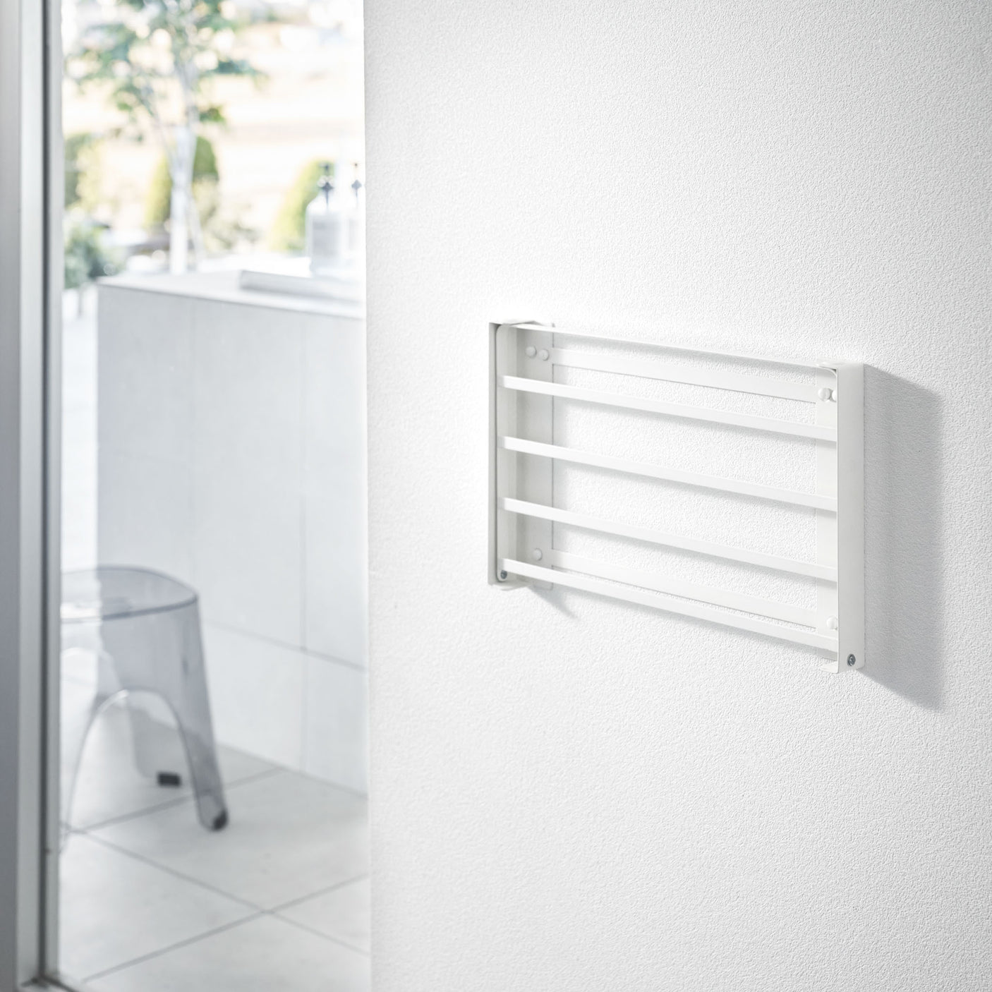 Hånd legger sammen hvit vegghylle i metall.