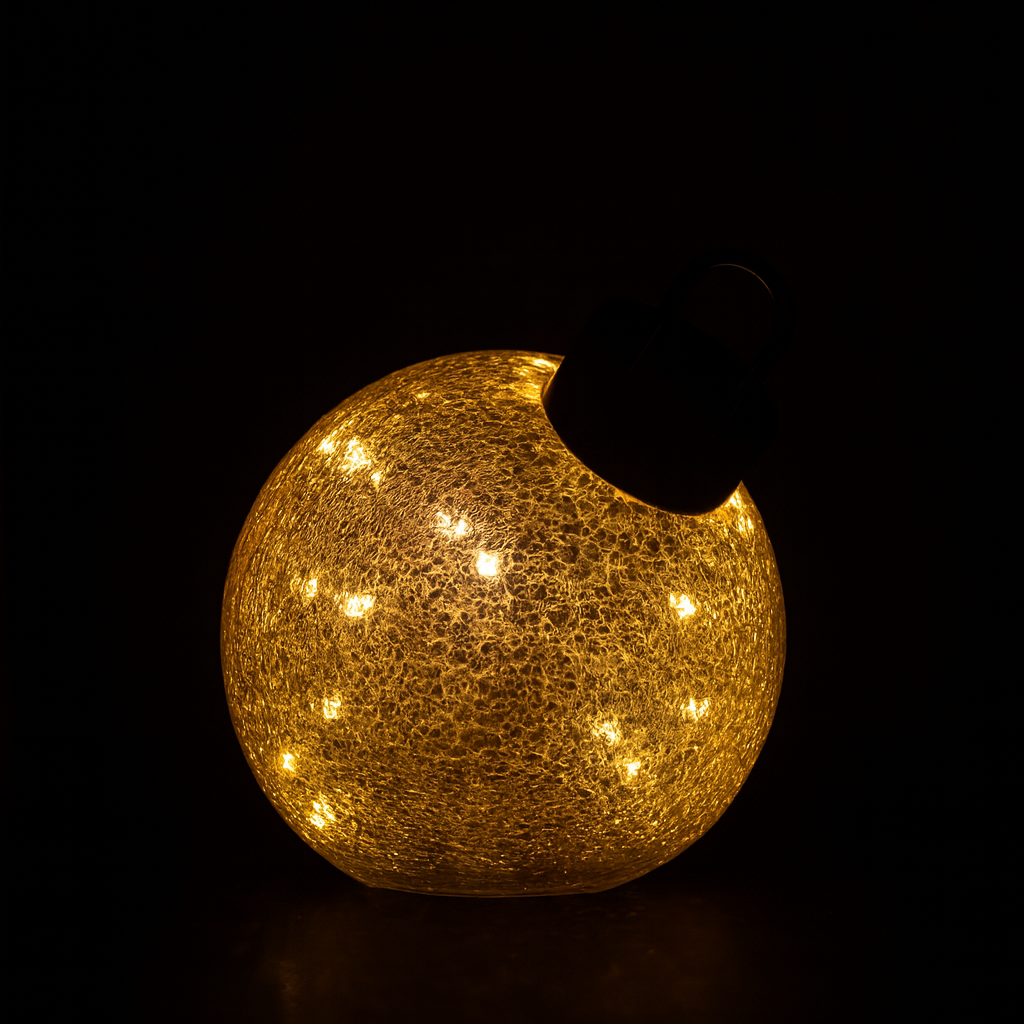 Miljøbilde av liten LED julekule i gull på bord.