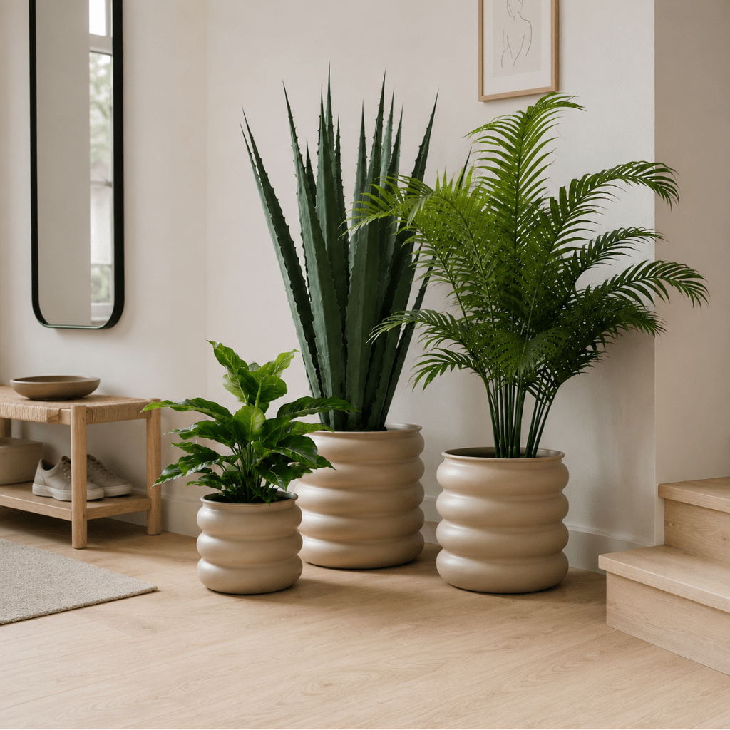 Tre lysebrune blomsterpotter med grønne planter plassert samlet i en moderne og lys stue. - Lindas dekor