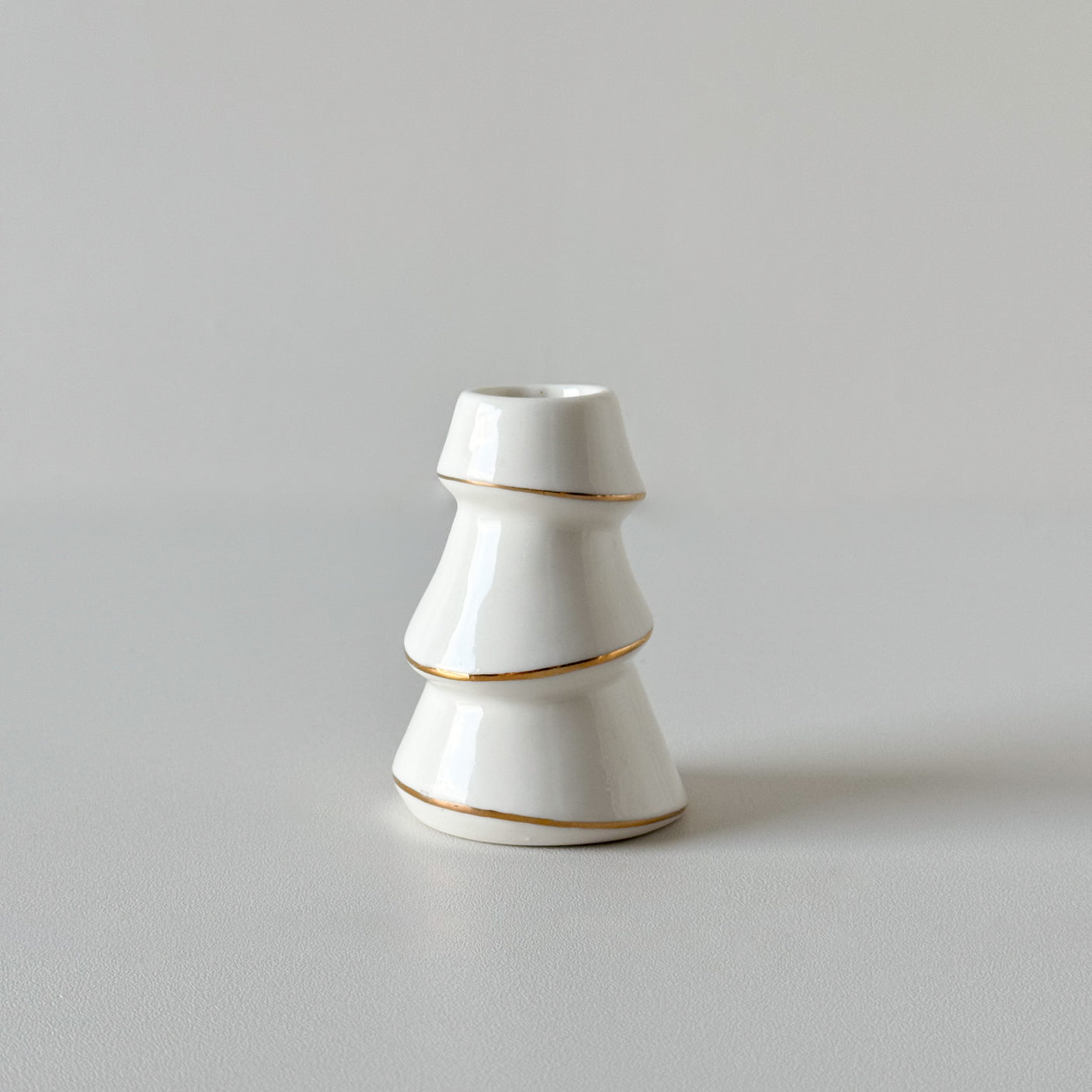 Liten hvit lysestake formet som juletre med gullkant