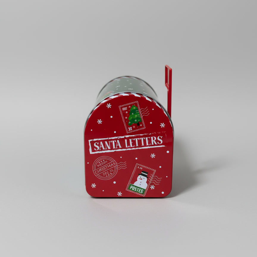 Grønn og rød julepostkasse brukt som dekor på bord med julelys i bakgrunnen