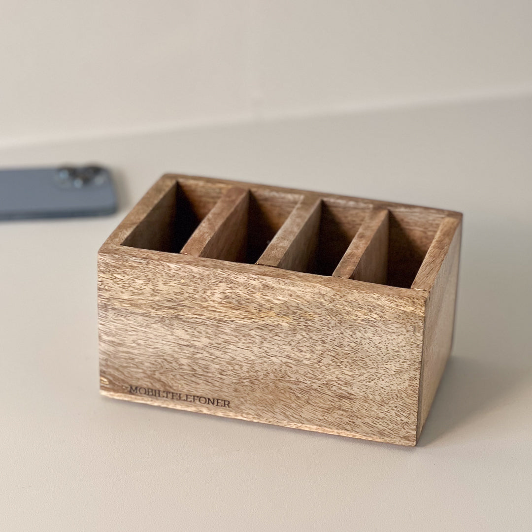 Elegant mobilholder i mangotre, stående på bord.