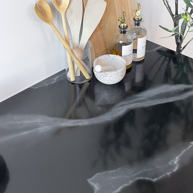 Klassisk sort marmor kontaktplast montert på kjøkkenbenk med dekor.