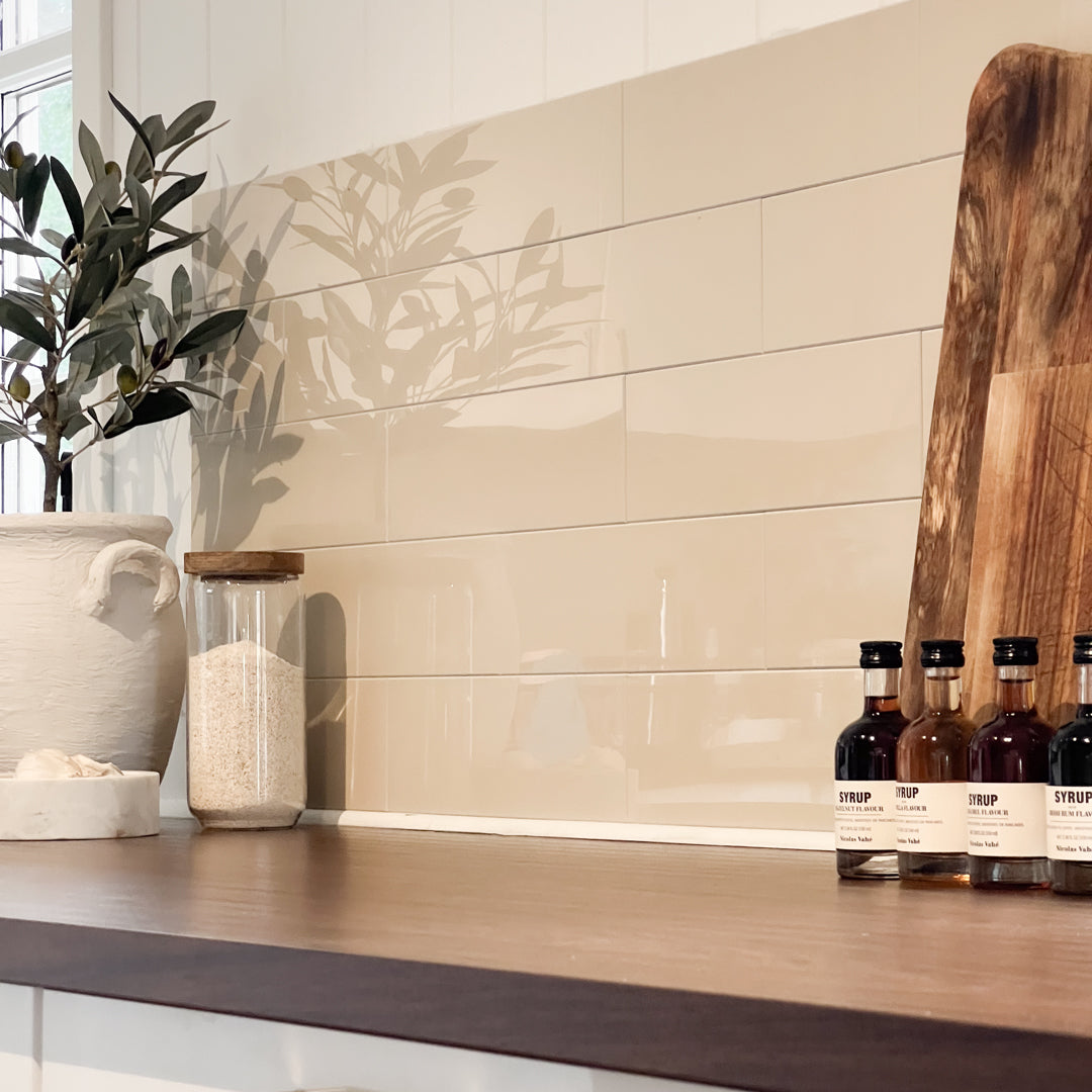 Selvklebende fliser i beige med blank finish, brukt som backsplash på kjøkken.