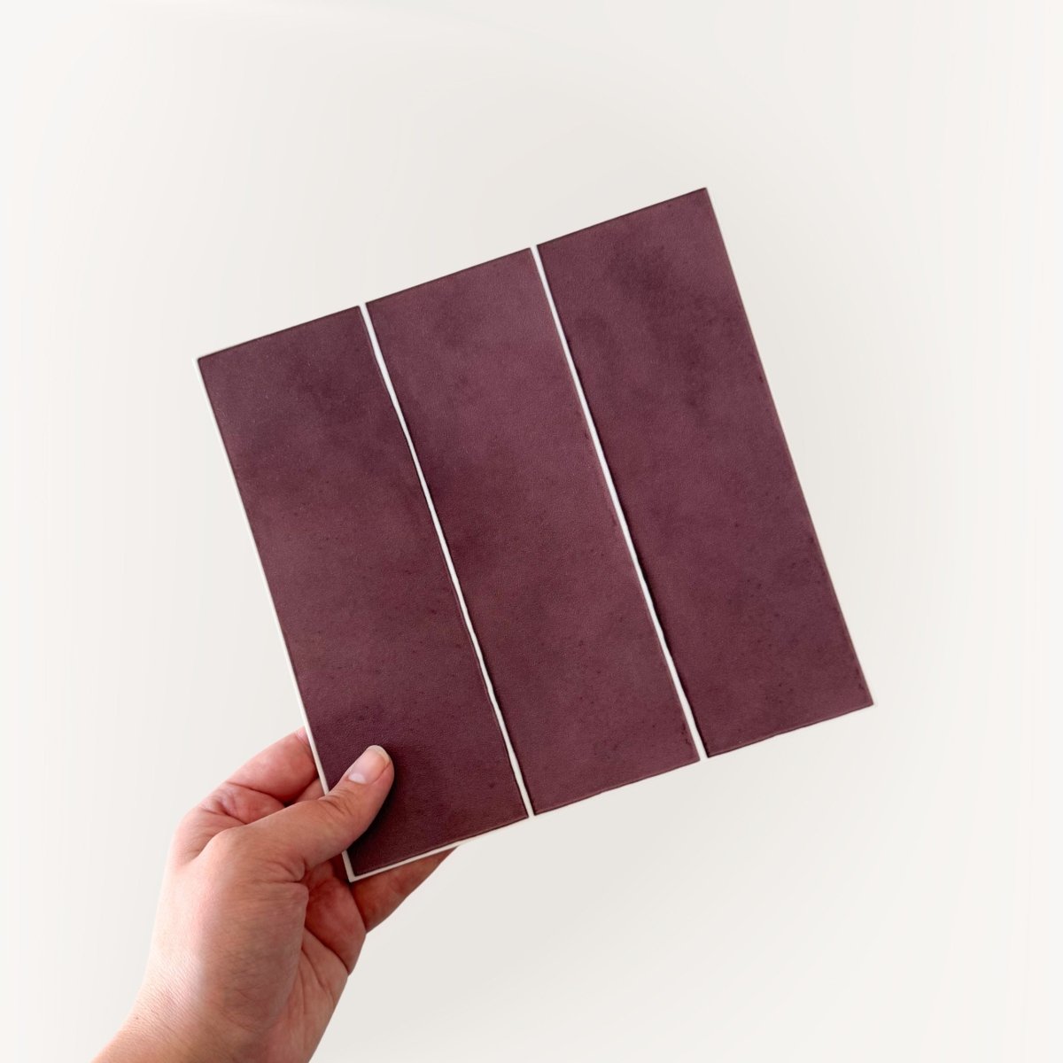 Katja vinrød selvklebende fliser imiterer fliser i en varm vinrød tone med hvite fuger. Passer godt til fornyelse av kjøkkenet.