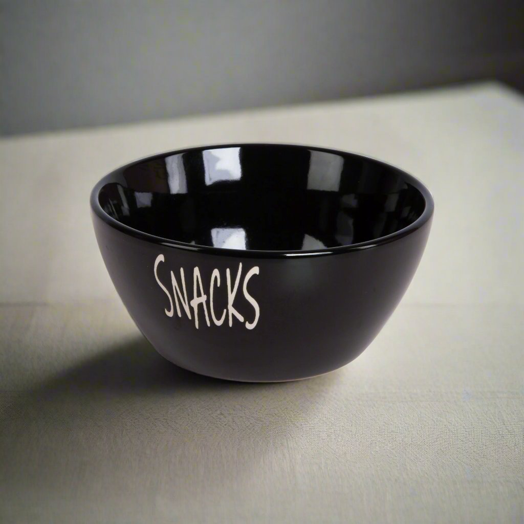 Keramisk snacks-skål i sort på lys bordflate, med myk belysning og skygge.