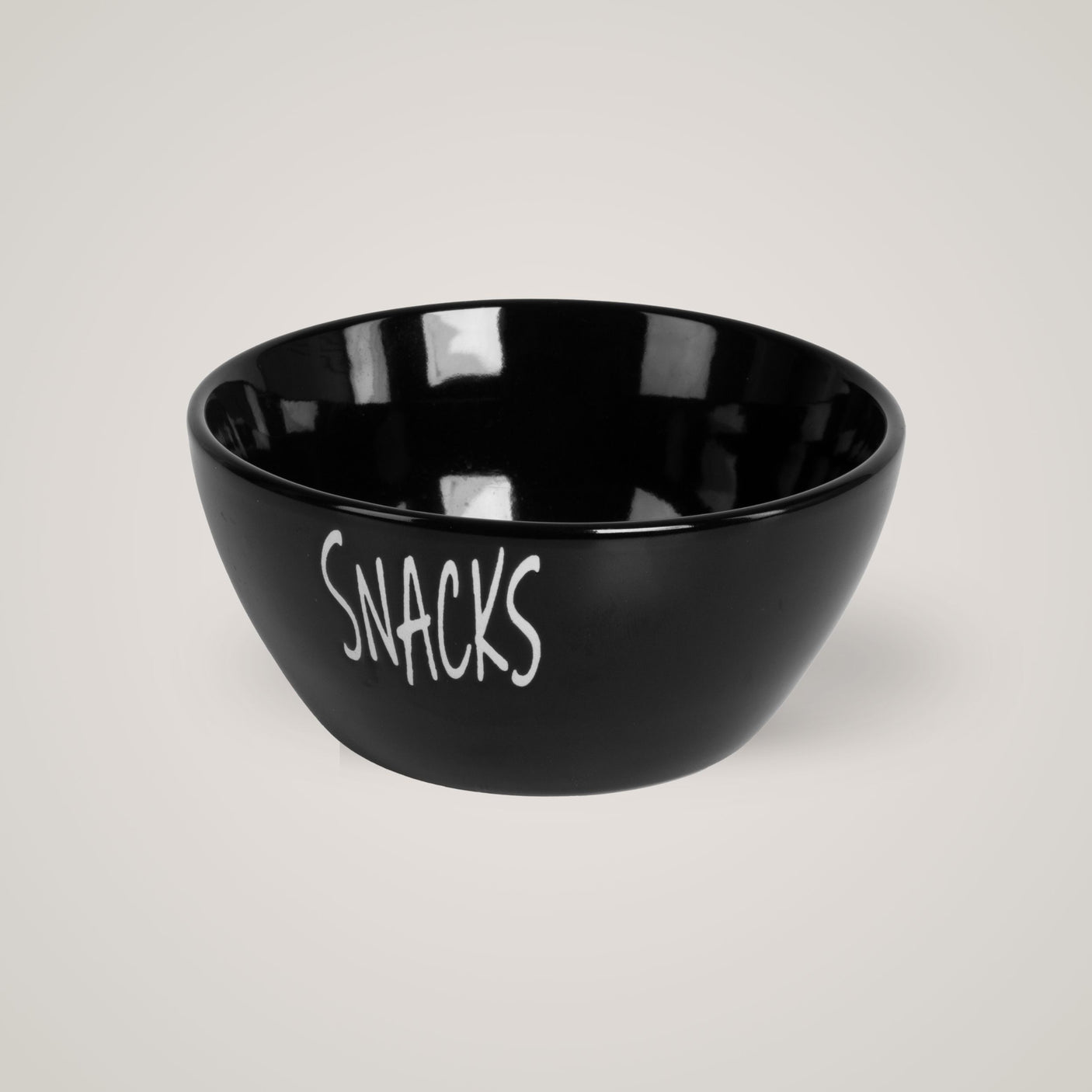 Sort snacks-skål med hvit tekst, plassert mot lys beige bakgrunn.