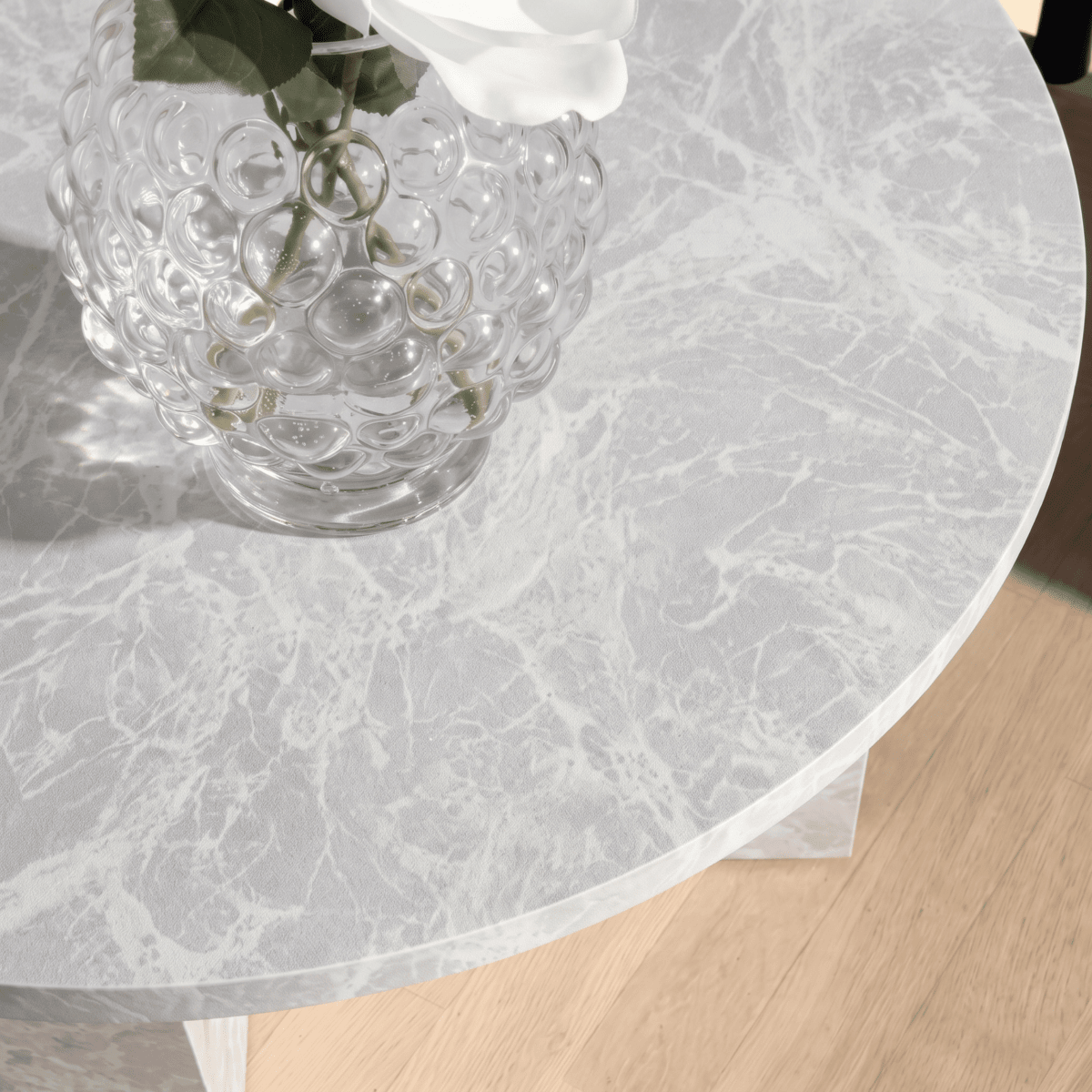 Rundt spisebord dekket med Limestone mist kontaktplast, lysegrå kalksteinslook med glassvase
