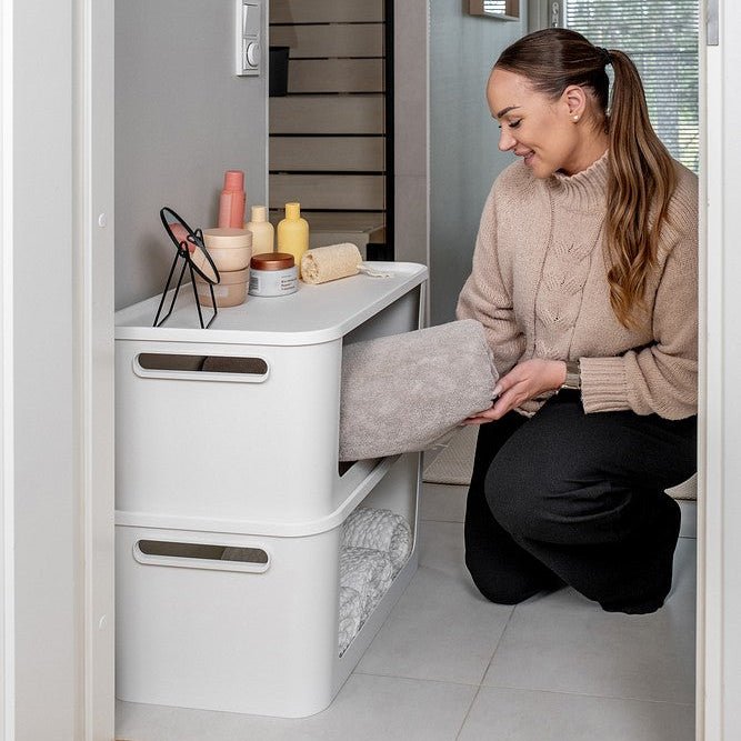 1. Kvinne som organiserer stablede hvite oppbevaringsbokser i garderobe