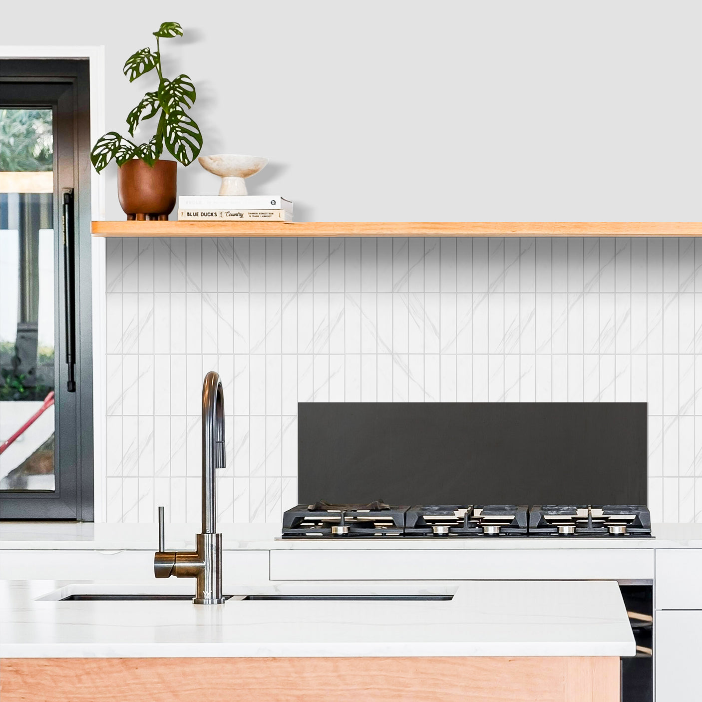 Kjøkken med hvit marmorfliser brukt som backsplash.