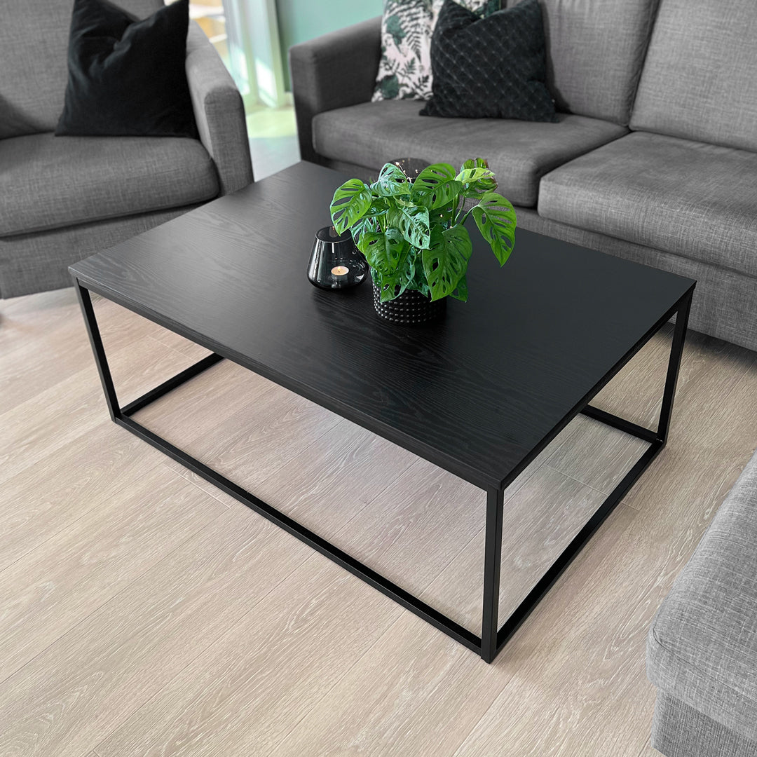 Sorte kontaktplast i trestruktur på stuebord – gir en matt og moderne finish som passer til grå sofa og stilfull stueinnredning.