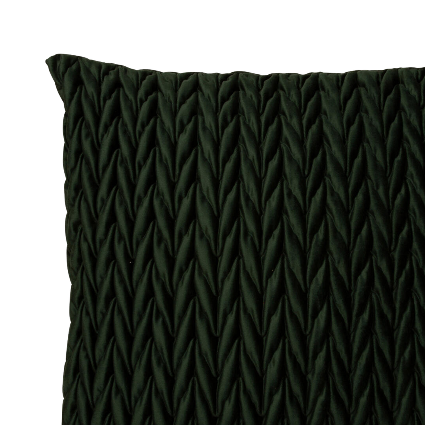 Flettet velur putetrekk i dyp flaskegrønn på lys sofa med dekor i bakgrunnen.