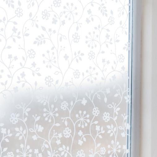 Vindusfolie med blomstermønster og blader på frosted bakgrunn