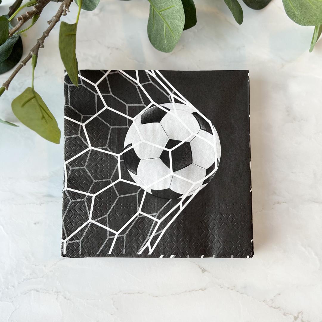 Nærbilde av serviett med fotballtema på tallerken i uformelt bordoppsett.