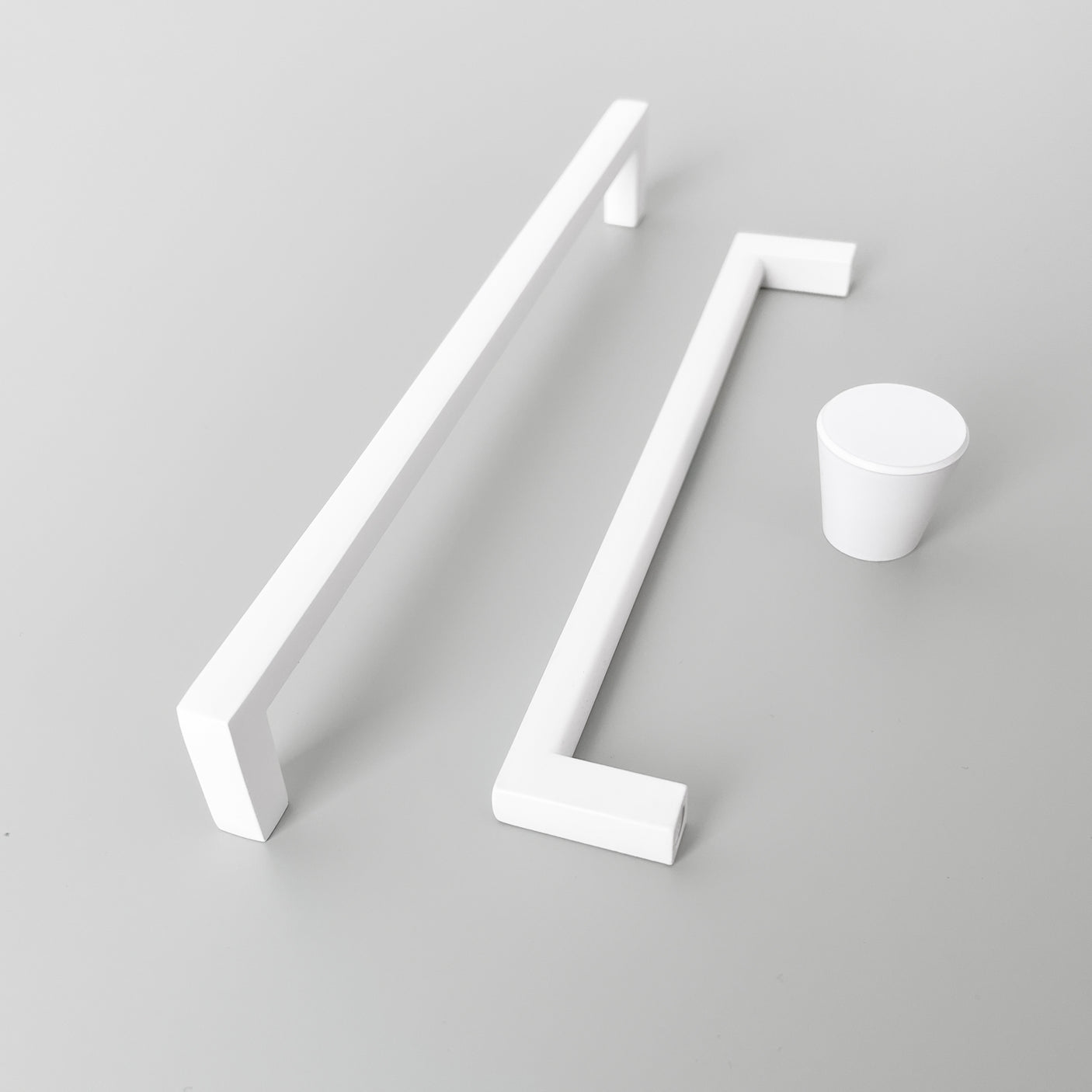 Hvitt håndtak i metall montert på lys kjøkkenfront