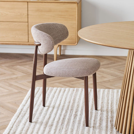 Levanto spisestol i sandfarget tekstil med ben i valnøttlook ved spisebord