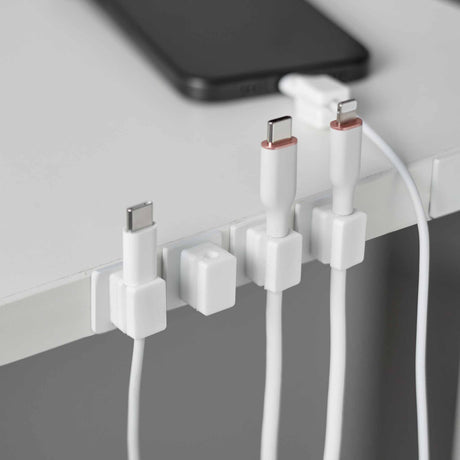 Hvite magnetiske kabelholdere med base for ryddig kabelstyring på skrivebord
