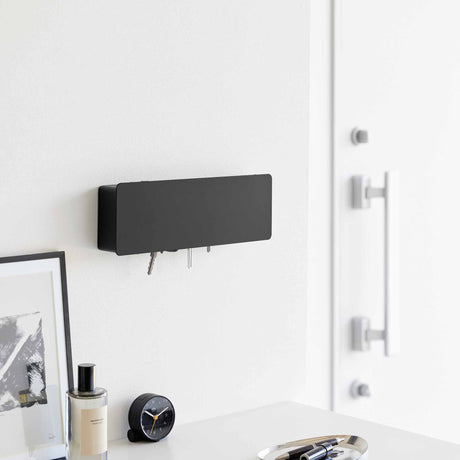 Veggmontert nøkkelskap i sort metall med diskré design