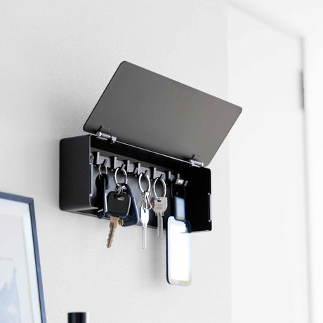 Sort vegghengt nøkkelskap med skjult front og åtte flyttbare kroker