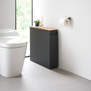 Sort oppbevaringsmøbel med lys treplate i moderne baderom.