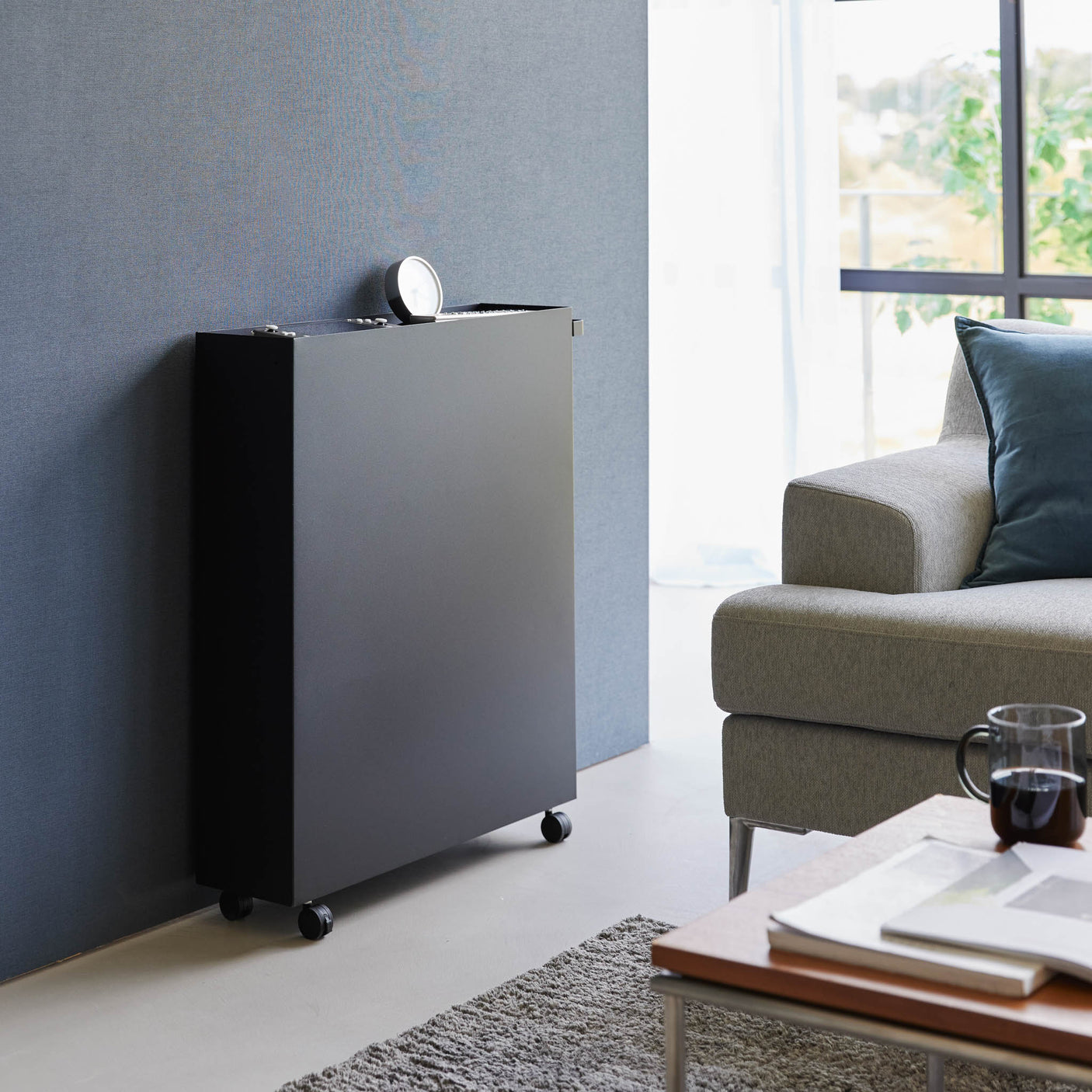 Praktisk oppbevaringshylle i sort metall ved siden av seng.